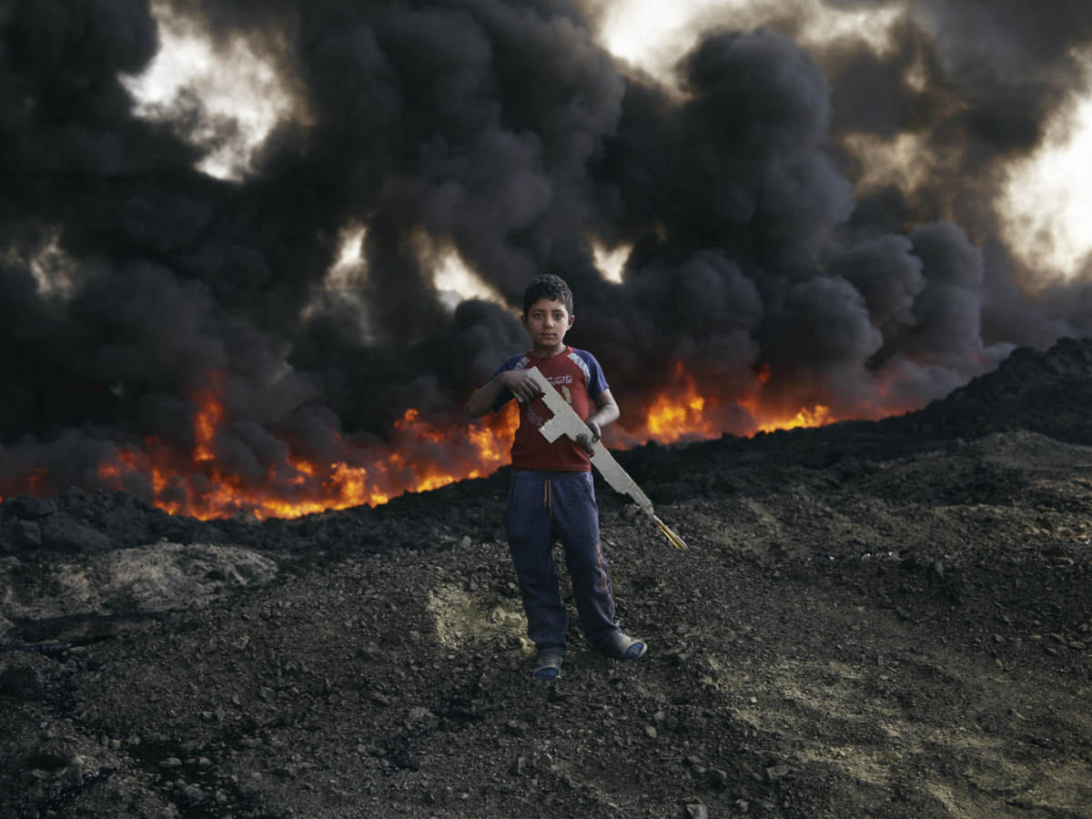 Zaer Ibrahim*, 8 plays by the burning oil fields in Qayyarah. Photo by Joe L. for Oxfam 