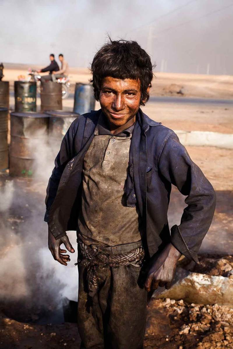 Young boy working at makeshift oil refinery in Hasakah, Syria, 2014